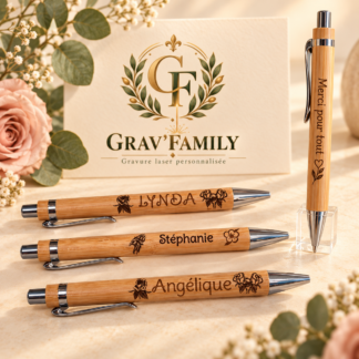 Exemples de stylos personnalisés avec prénoms, un stylo debout gravé Merci pour tout et le logo Grav’Family en arrière-plan.